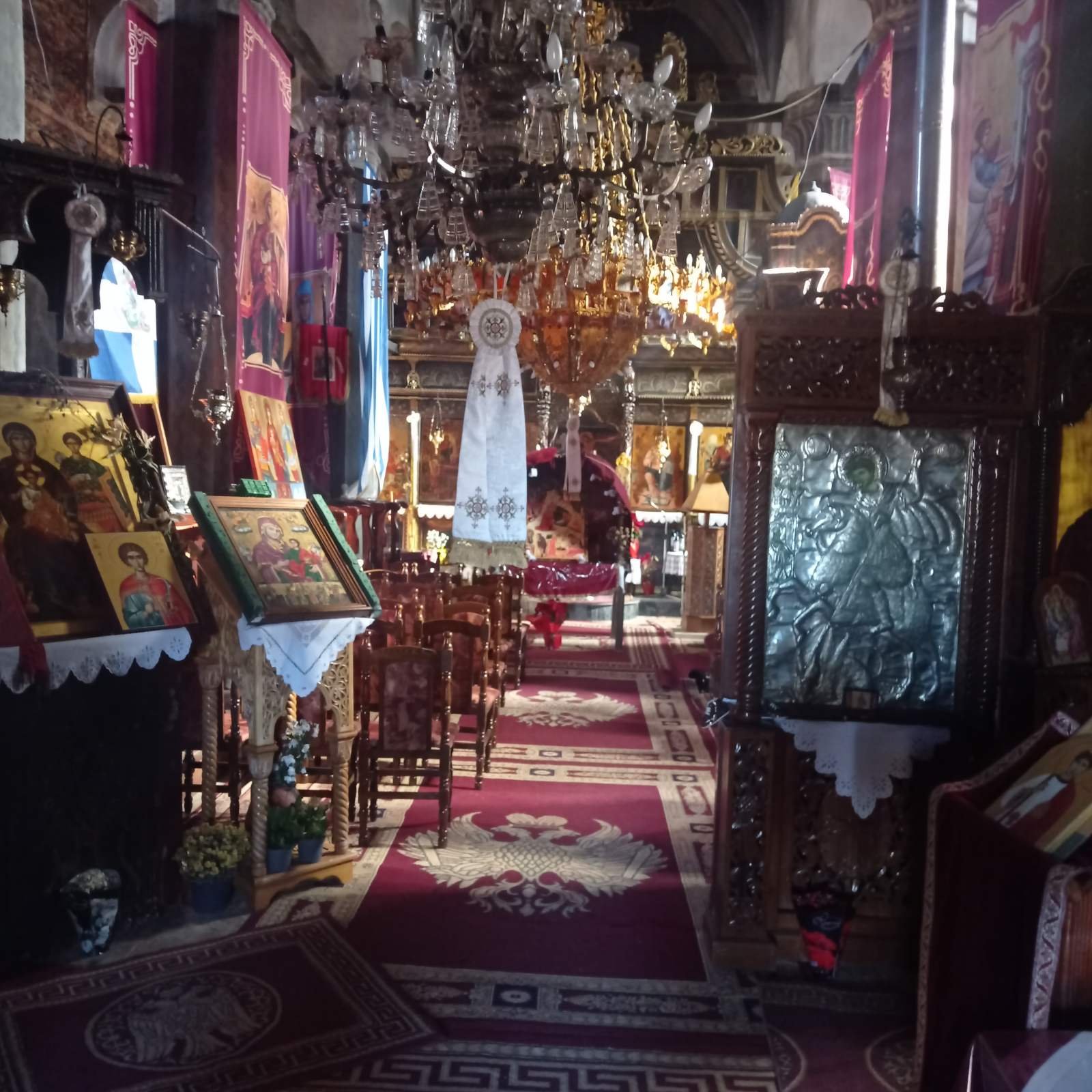 Traditional stone chapel with red-tiled dome and mountain backdrop near Kerkini